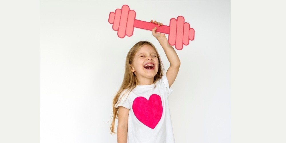 student with a shirt with a heart holding up a virtual dumbell