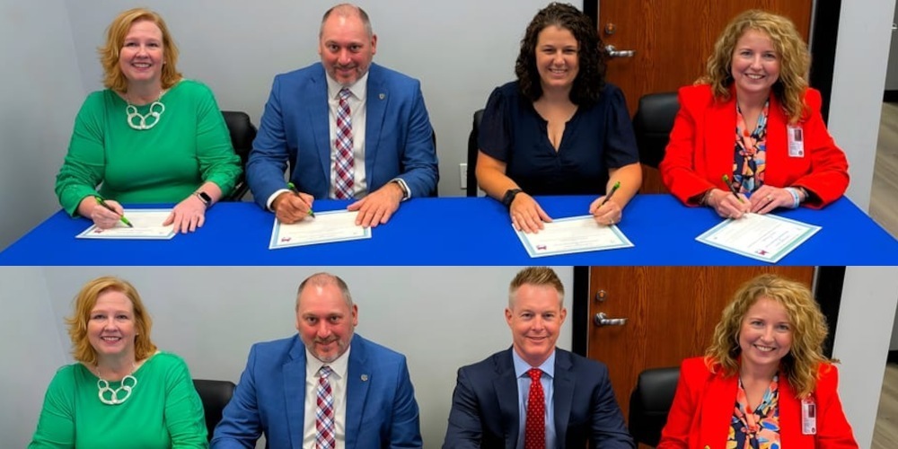 school and business leaders seated at a table for a partner in education signing