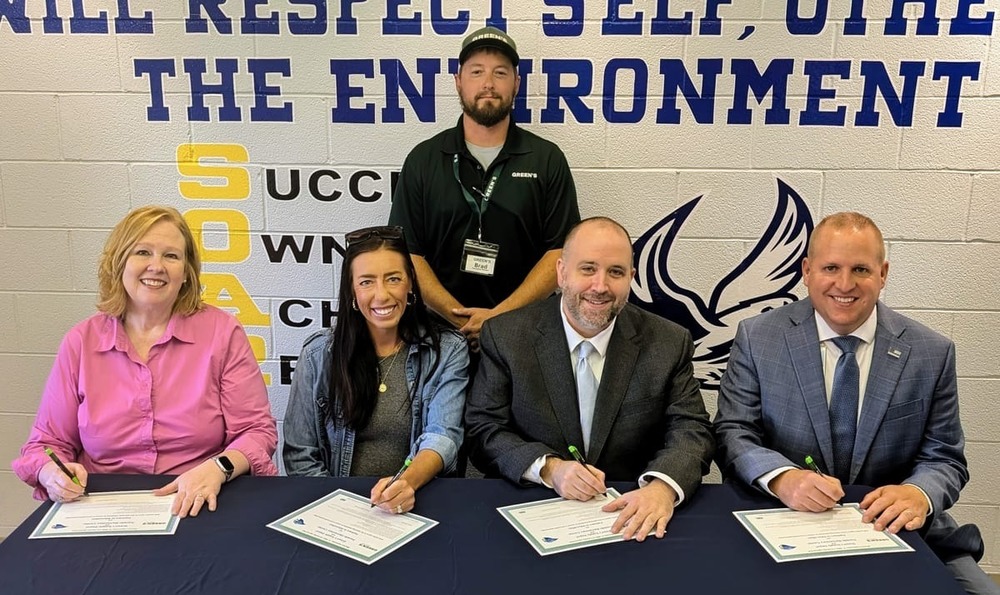 business and school leaders signing school business partnership agreement