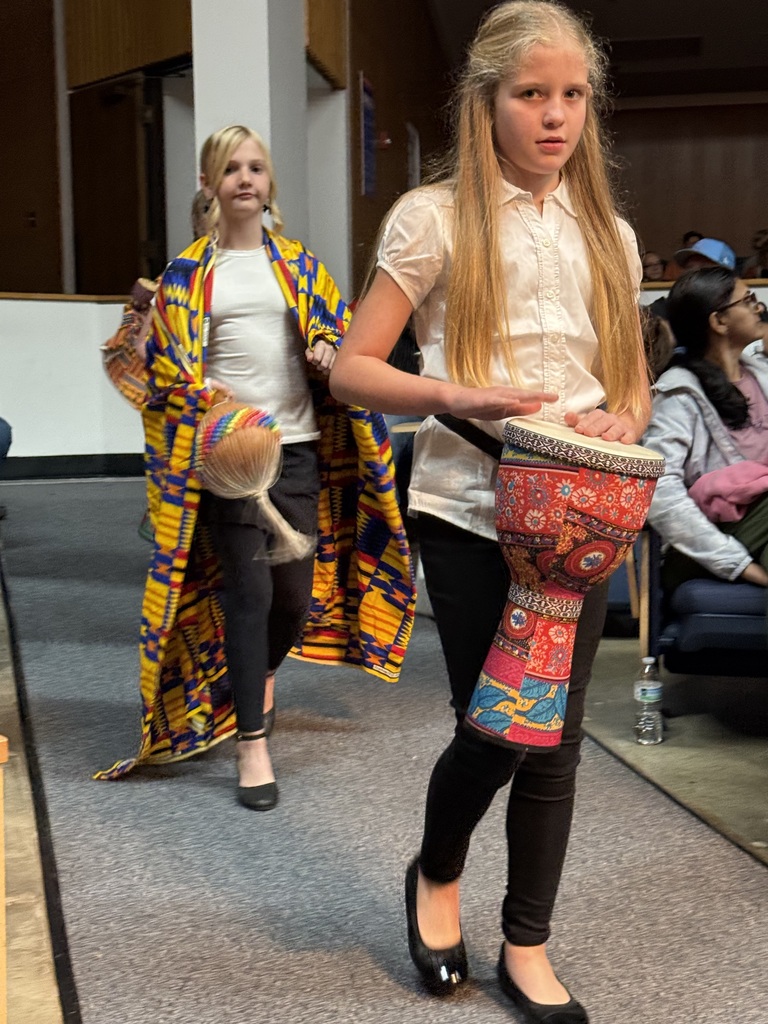 two students with drums walking down aisle