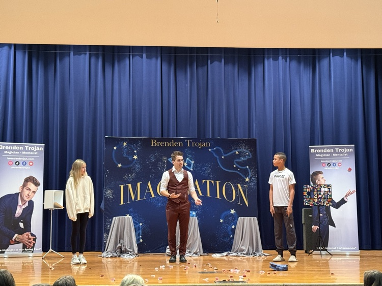 two students on stage with magician