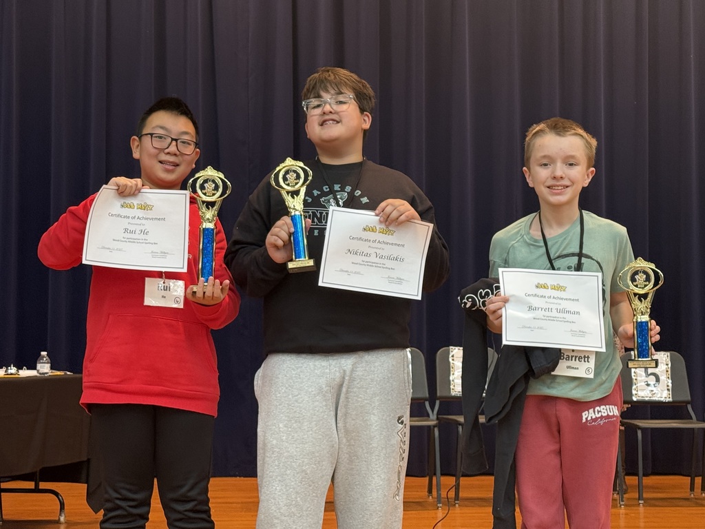 three students with certificates and trophies from spelling bee