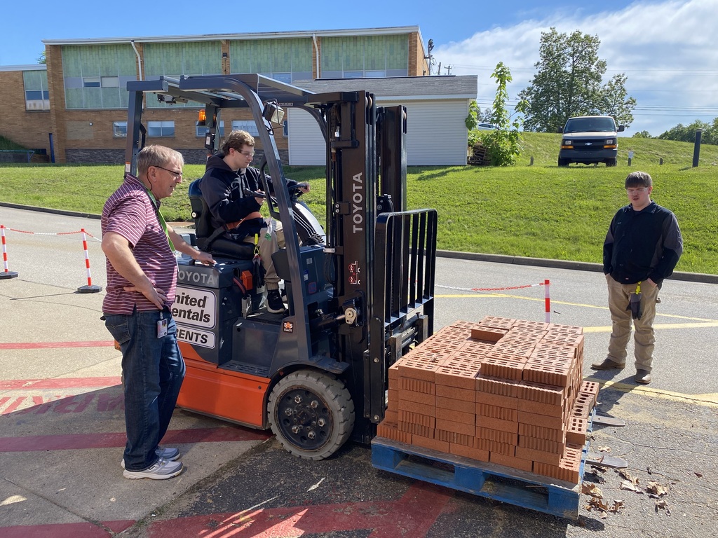 Image of student operating a forklift while teacher observes.