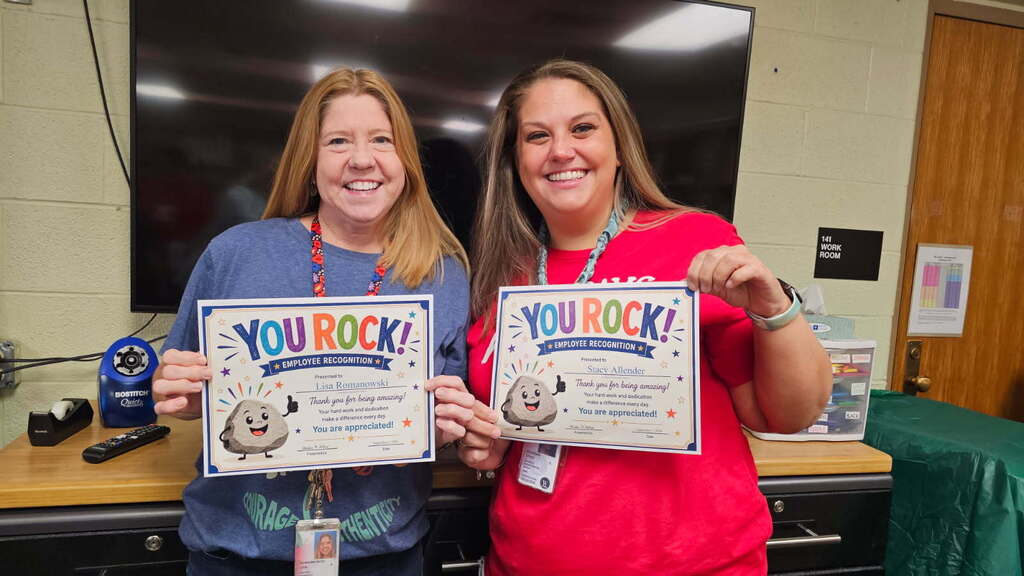 two women posing for the camera and holding certificates