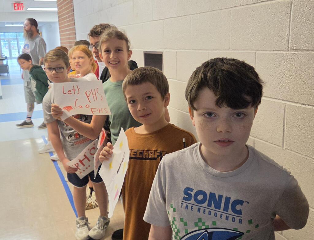 Line of students holding signs made for the high school.