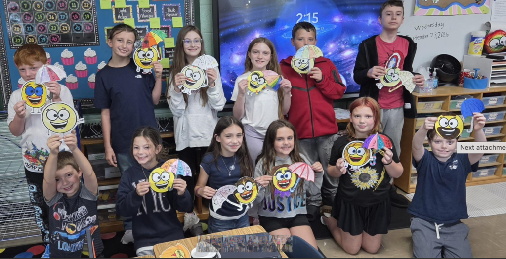 Fourth grade class holding up their little spot of optimism artwork.