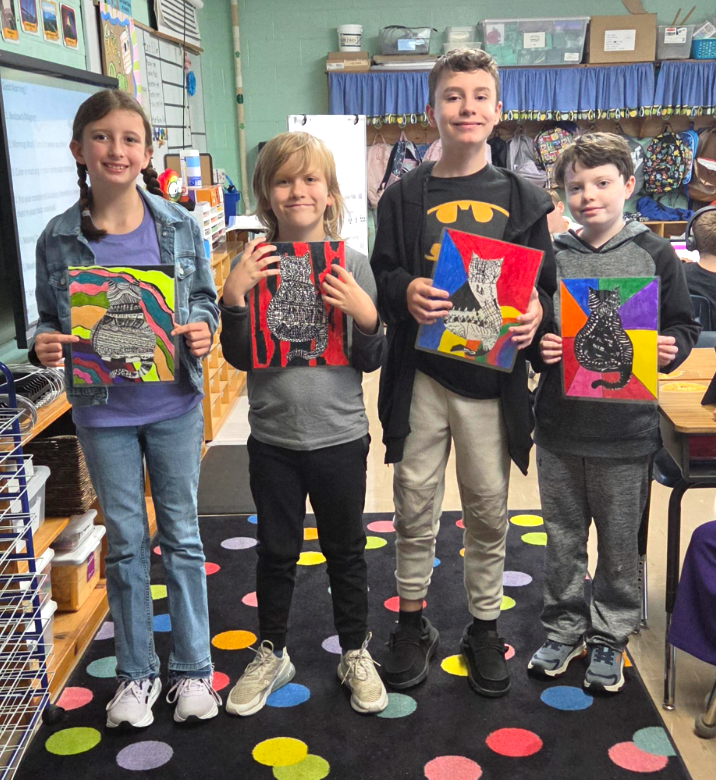 Four students, (L-R girl, boy, boy, boy) smiling and holding their zentangle cat artwork.