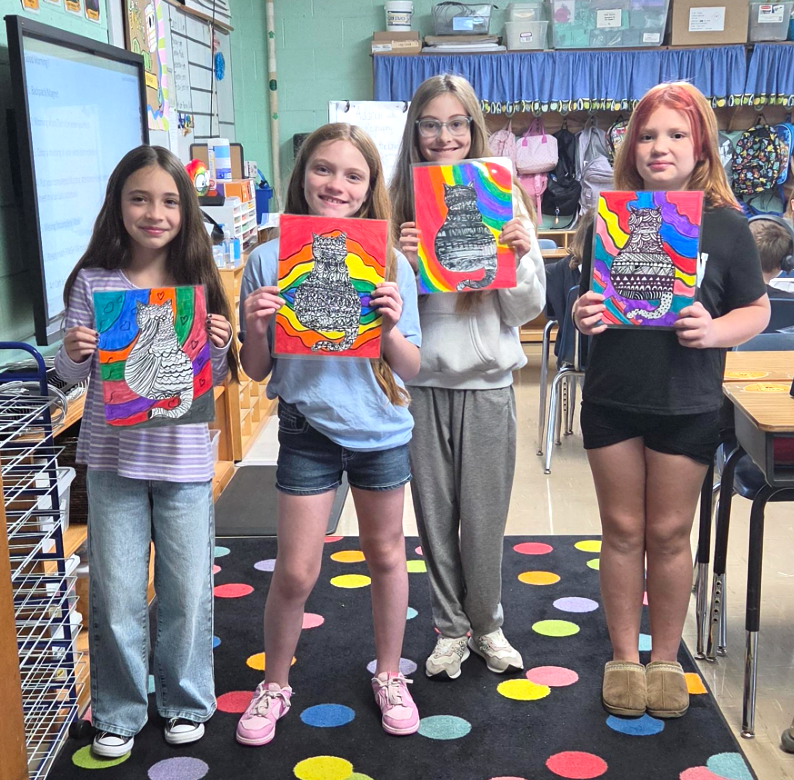 Four students, (all girls) smiling and holding their zentangle cat artwork.