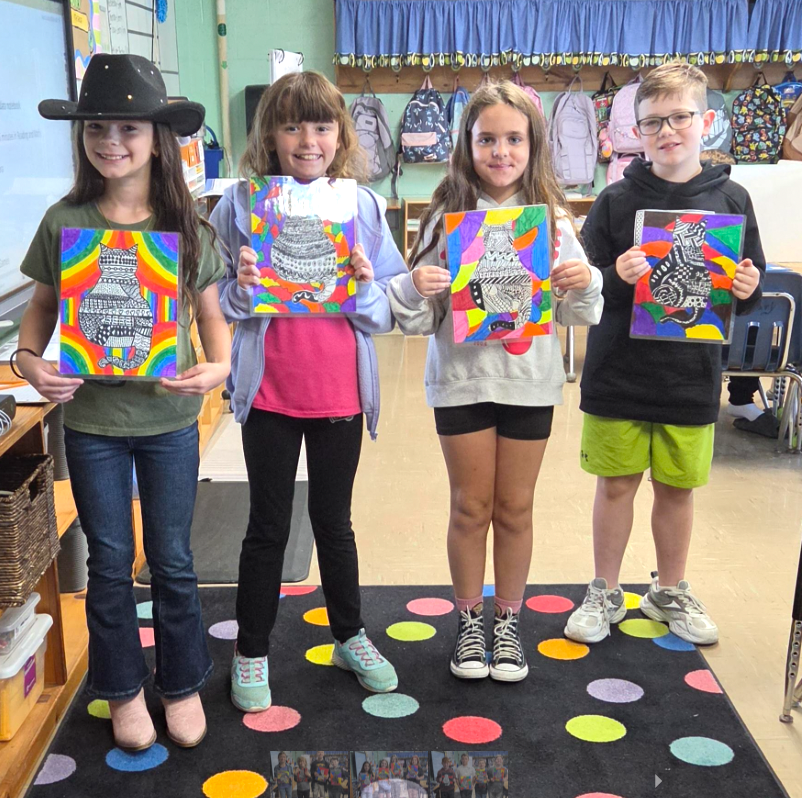 Four students, (L-R girl, girl, girl, boy) smiling and holding their zentangle cat artwork.