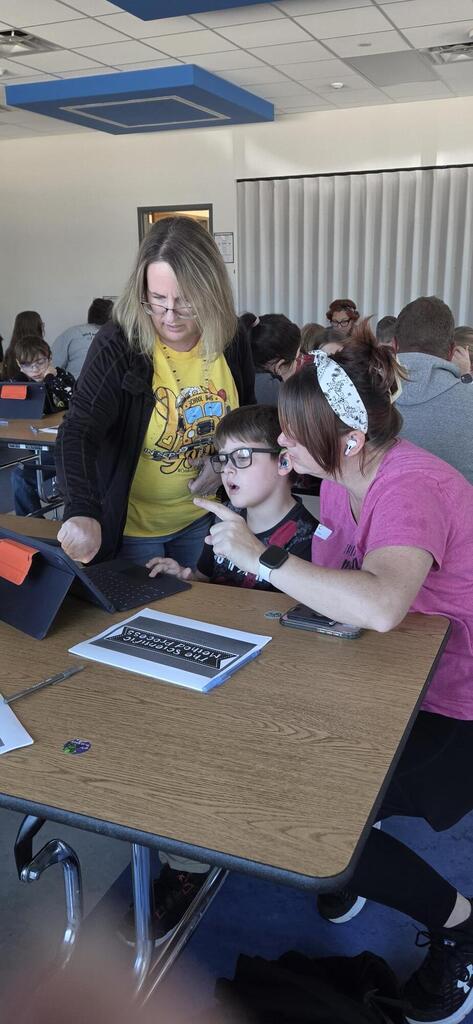 Parent and teacher helping a student do science fair research.