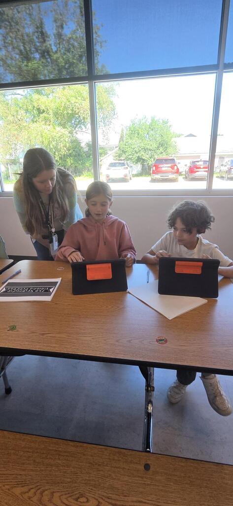 Teacher helping two students do science fair research.