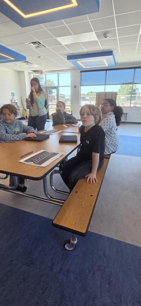 Four students watching teacher who is presenting.