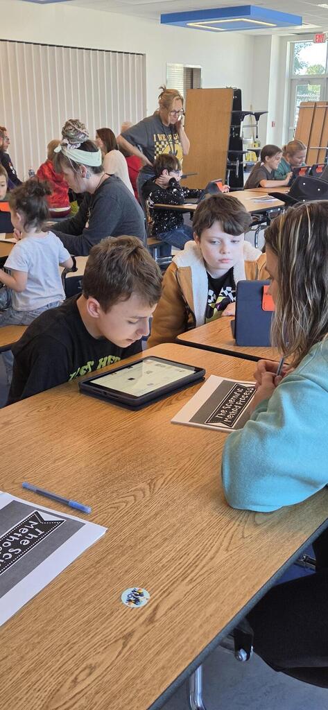 Parent helping two students do science fair research.