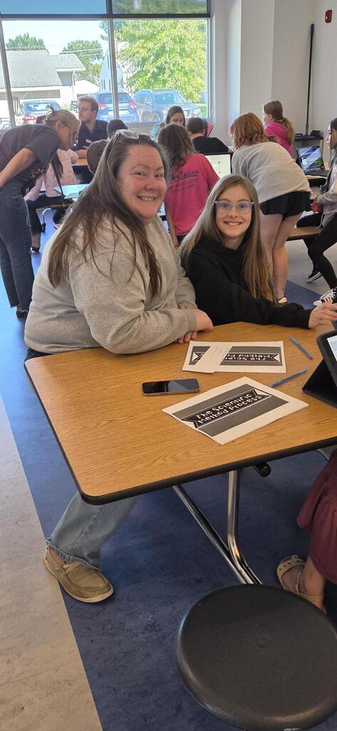 Mother and daughter smiling as they listen to the science fair presentation.