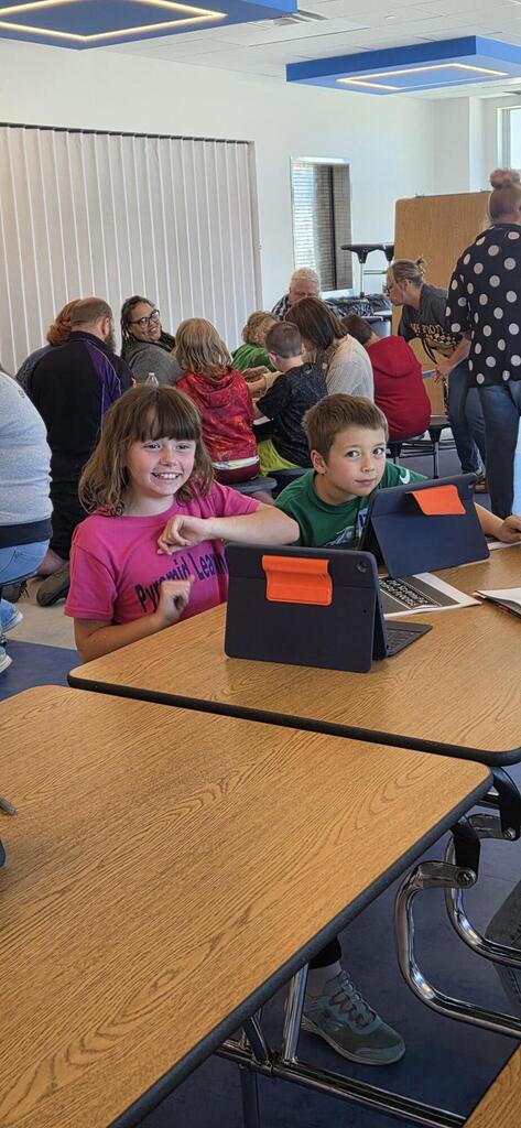 Two students smiling as they listen to the science fair presentation.