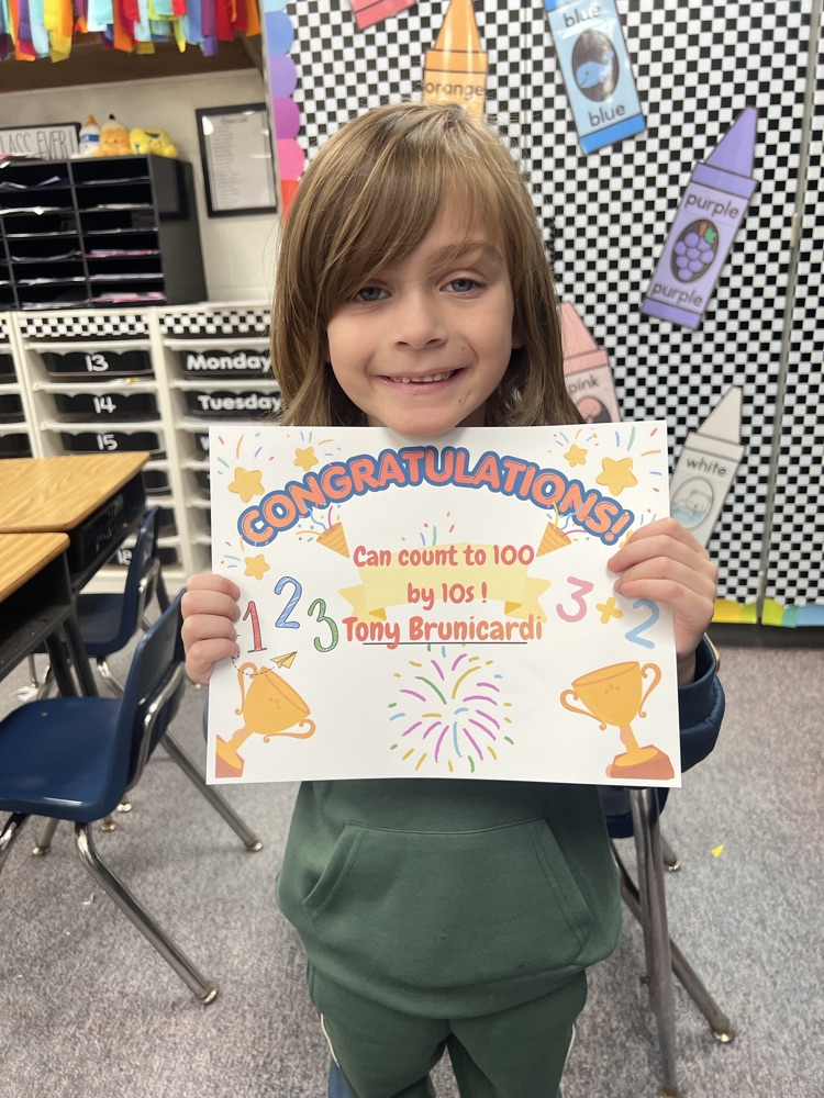 A male student poses with his certificate for counting to 100