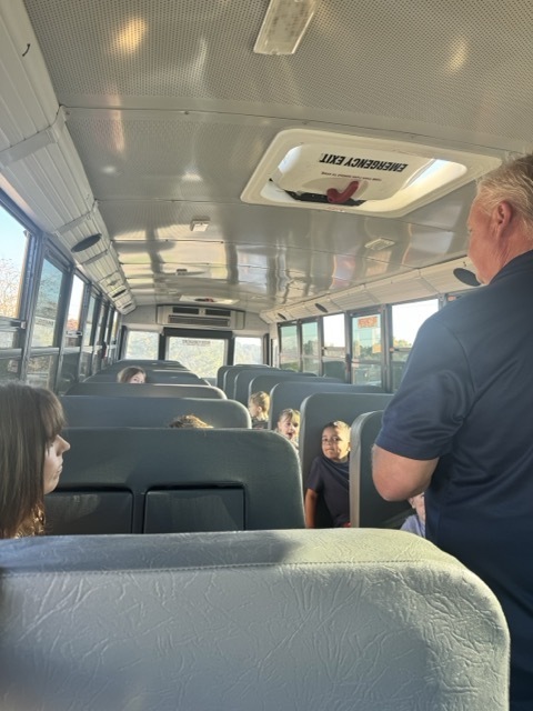 man standing on a bus speaking to students
