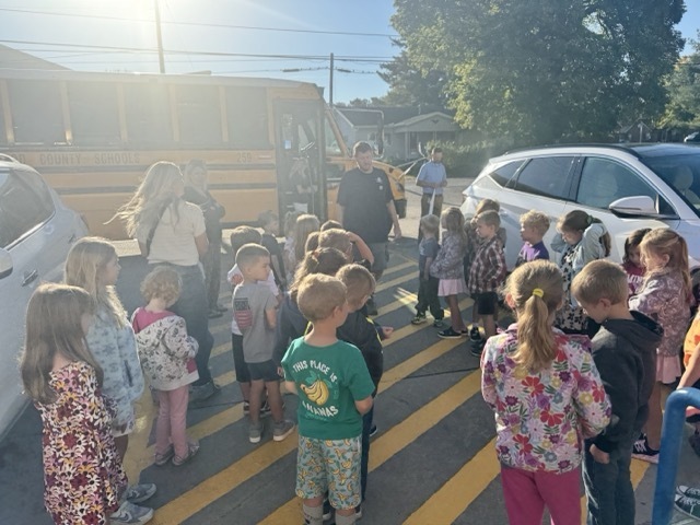 man, standing in front of school bus, speaking to students