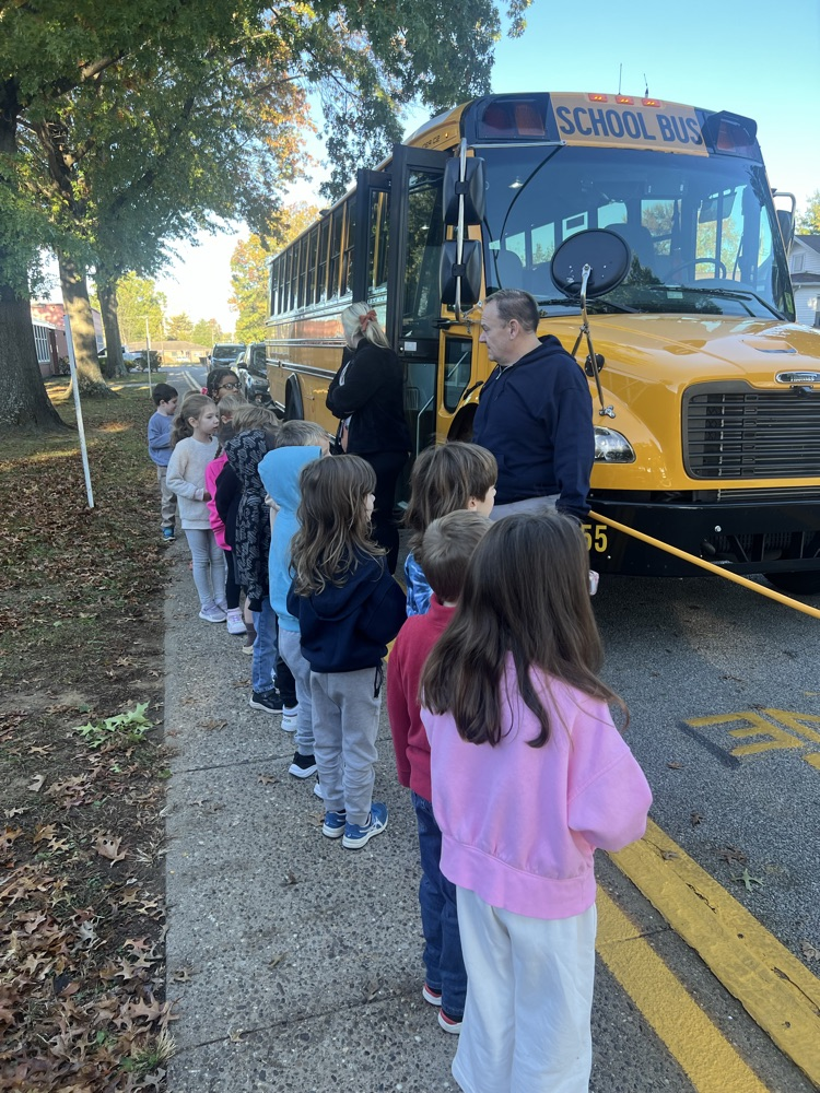 Kindergarten students standing beside a bus to learn about bus safety