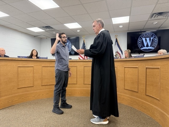 judge jason wharton stands swearing in board member simon hargus