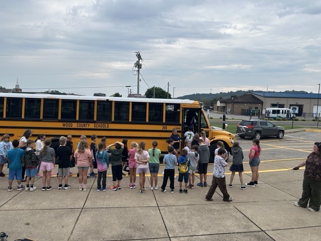 students standing in front of a yellow school bus