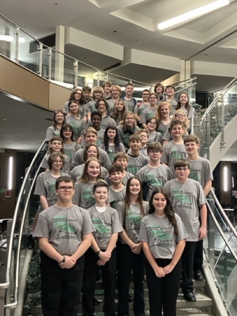 band students, dressed in the same gray and green shirts, standing on a descending stairway