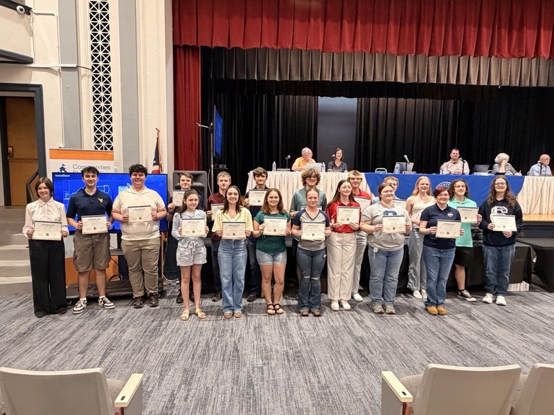 Group of students receiving an award and holding their certificate in front of the Board of Education