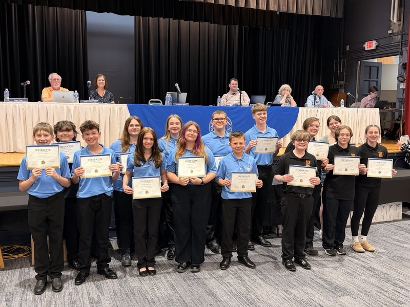 Group of students receiving an award and holding their certificate in front of the board of education