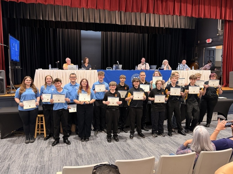 Group of students receiving an award their certificate in front of the Board of Education