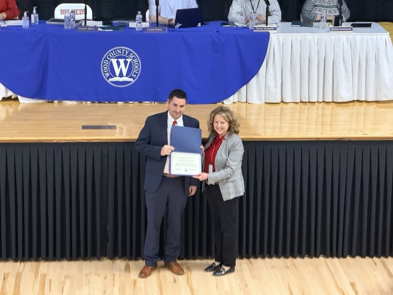 teacher of the year winner, Sam Vincent, appears and holding a certificate, with superintendent Christie Willis in Parkersburg High School Auditorium