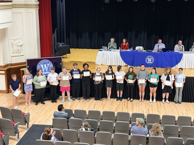 students standing in front of Parkersburg High School Auditorium and receiving certificates for music/choral awards