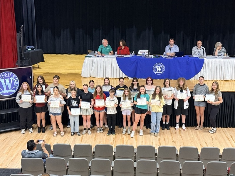 students standing in front of Parkersburg High School Auditorium and receiving certificates for music/choral awards
