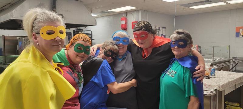 cafeteria workers dressed as super heros to celebrate school lunch hero day