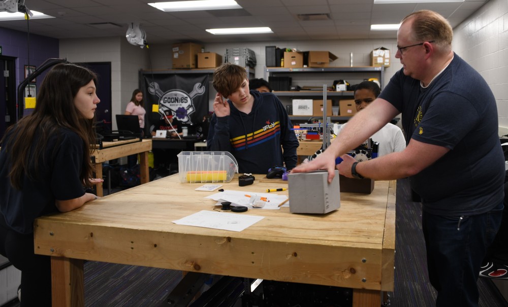 students and adult working in robotic lab
