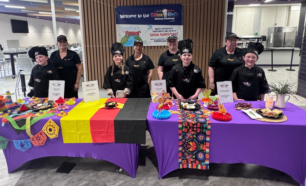 students and staff behind table for future chefs competition