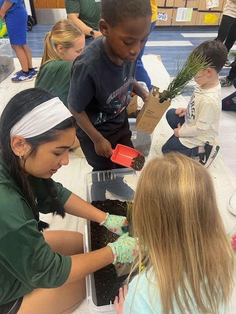 volunteers helping students plant trees