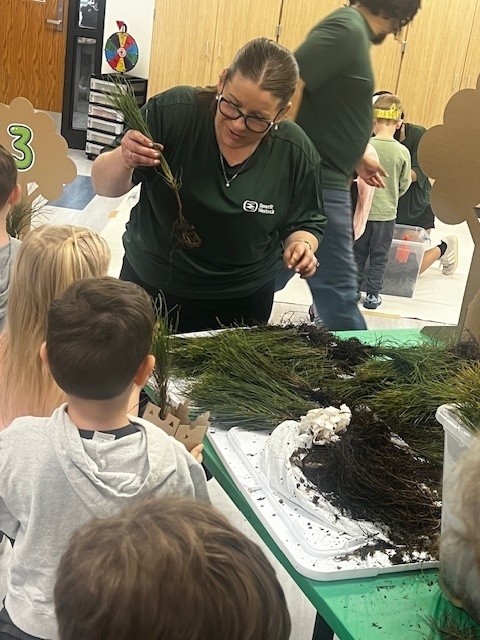 woman helping students plant trees