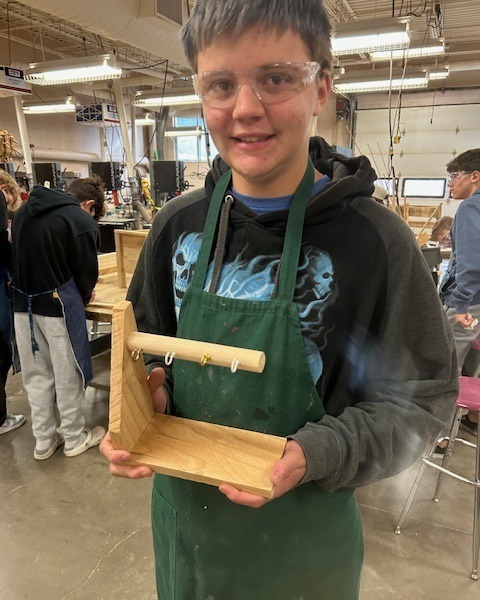 Student showing off his wooden key holder that he made in Woodshop