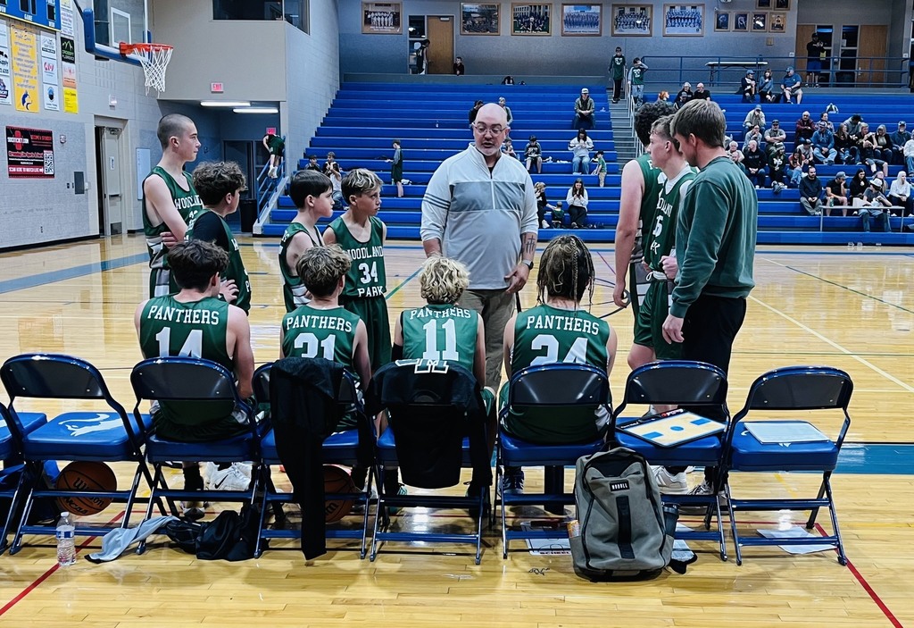 Jr High School boys basketball team and their coach talking during a game time out