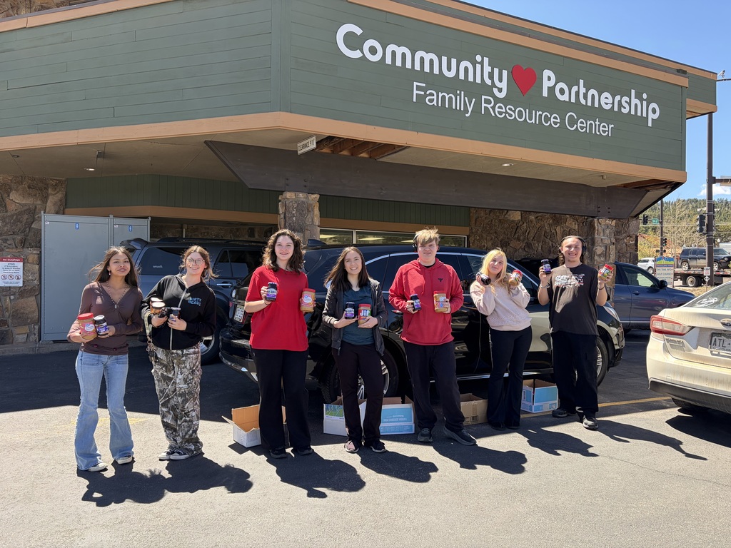 Seniors posing outside of Community Partnership to drop off jars of peanut and jelly