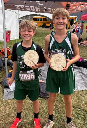 Two cross country athletes with trophies