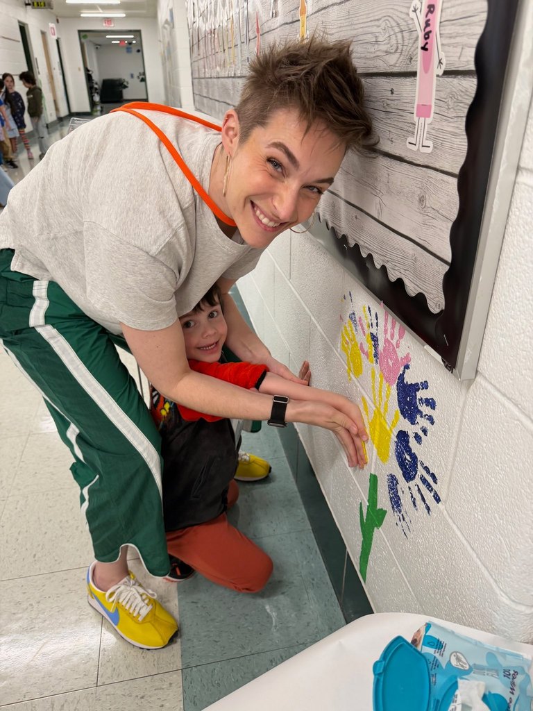 parent volunteer in the classroom helping students paint
