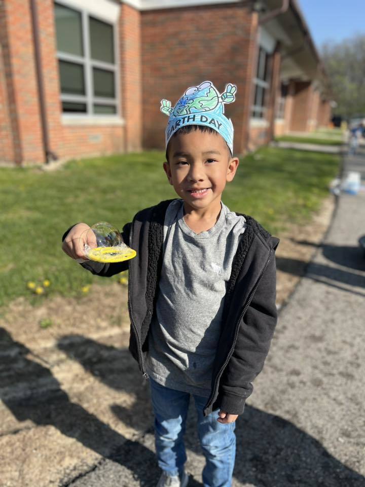 student with bubbles and earth day crown 