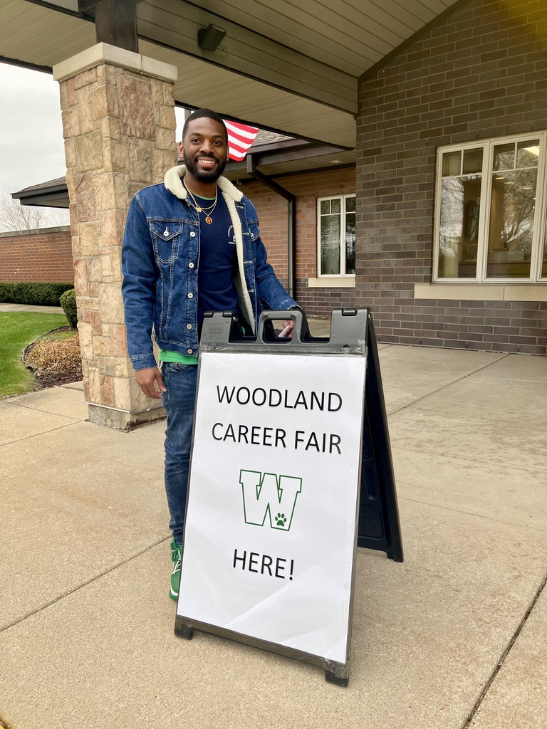Employee stands next to "Woodland Career Fair HERE!" sign April 2025