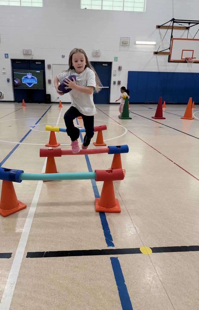 Football unit in PE - girl jumps over hurdles with football
