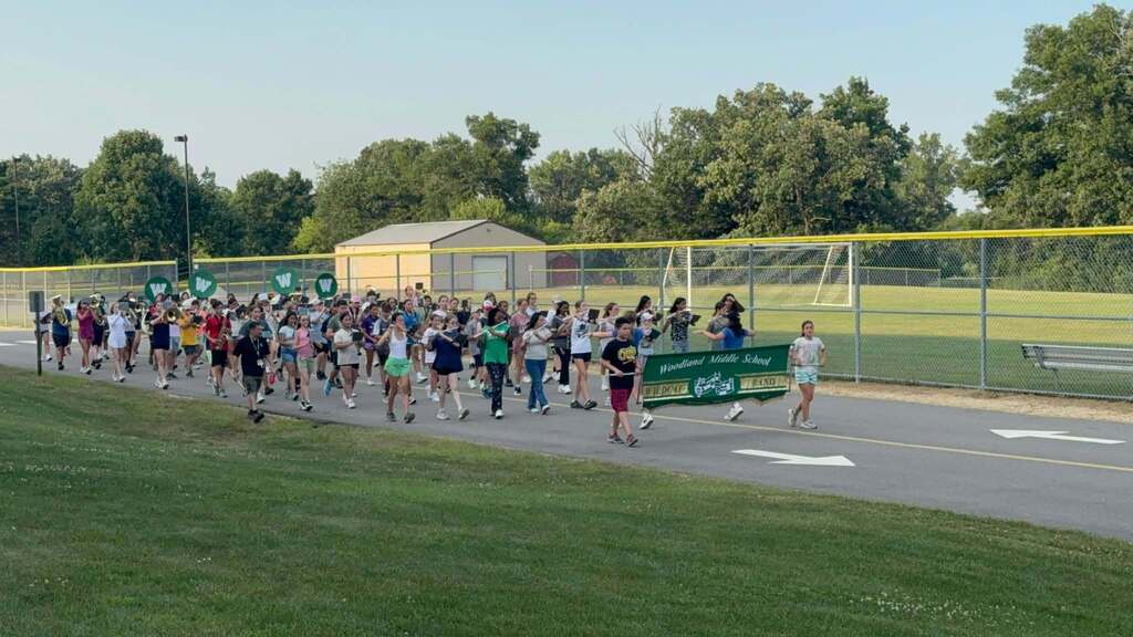 Students march with instruments past the soccer field while  attending "Marching Band Camp" in Aug. 2025