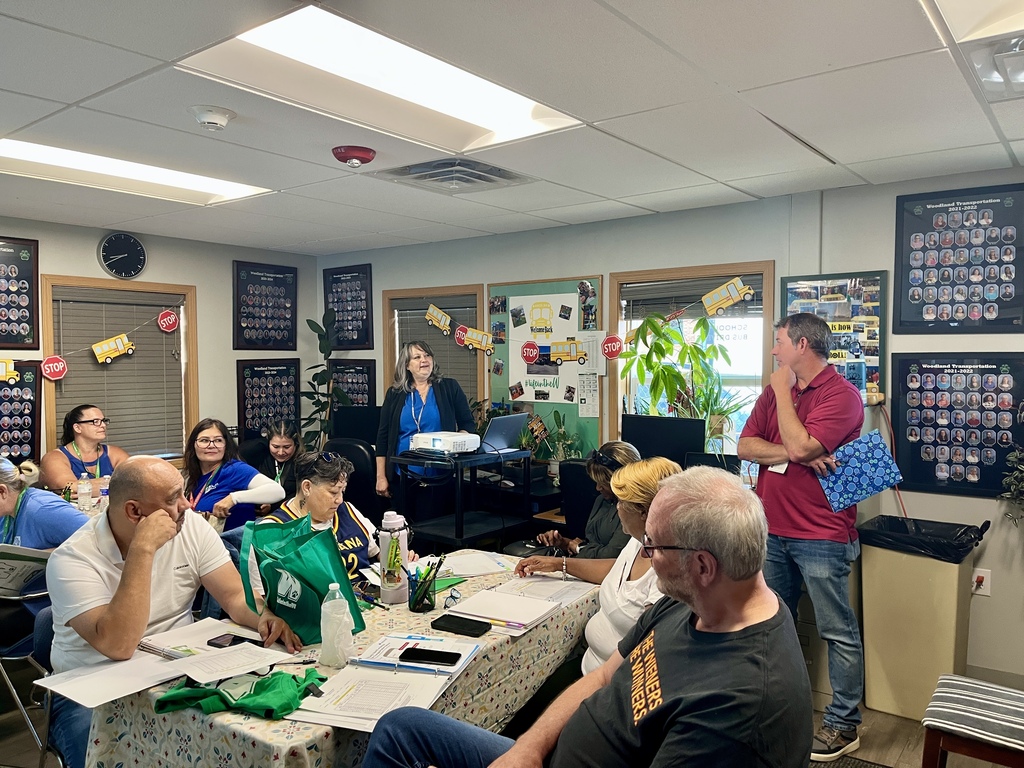New bus drivers sit at tables in a conference room for orientation
