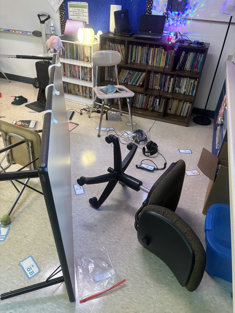 A desk overturned in a classroom with flashcards scattered about
