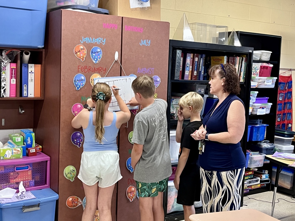 Students work together to solve a complex math problem on the whiteboards around the classroom