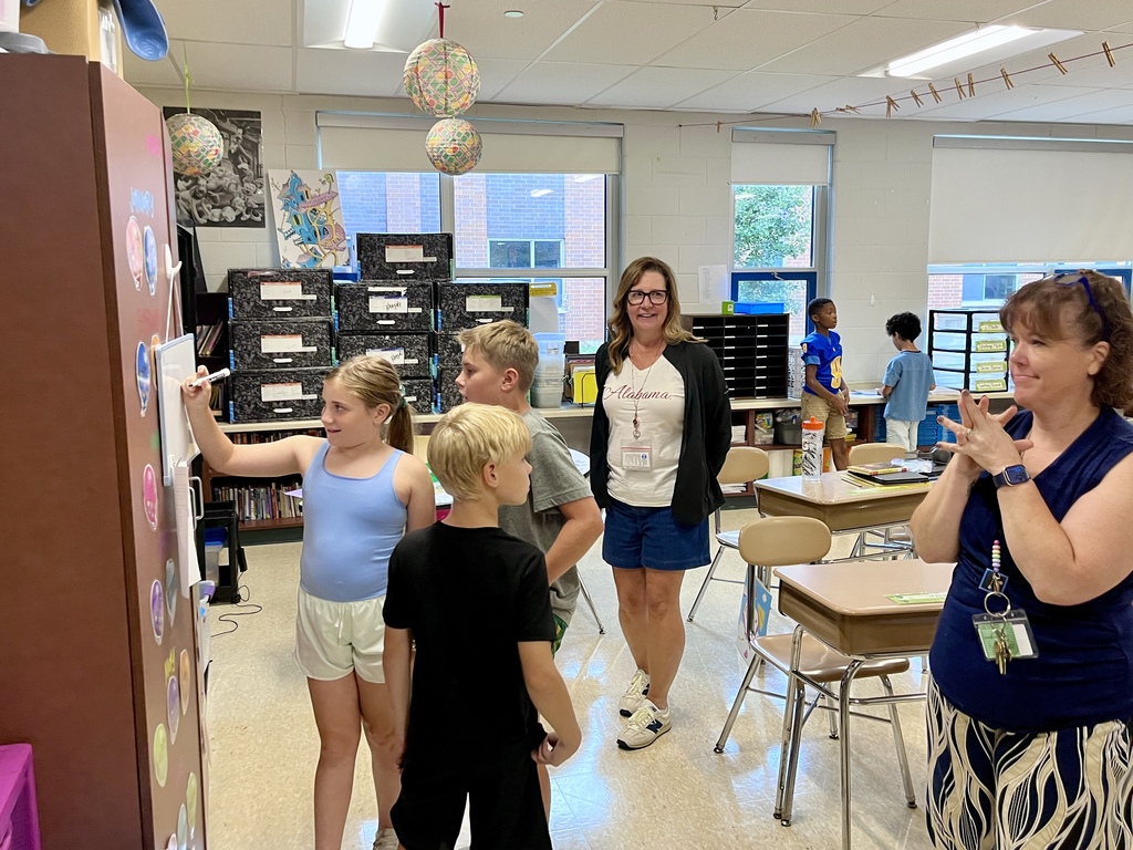 Students work together to solve a complex math problem on the whiteboards around the classroom